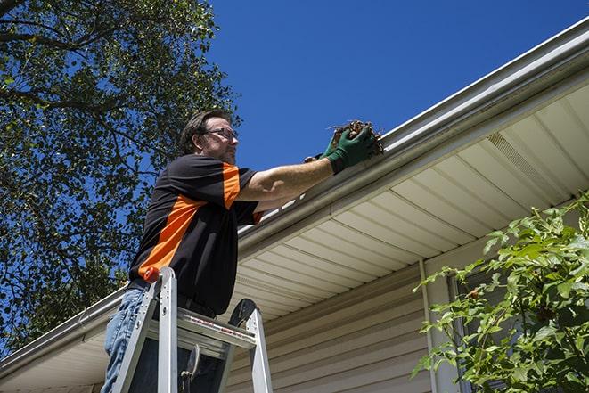 a repairman working on a broken gutter system in Brighton